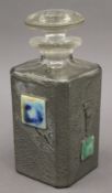 An Art Deco pewter clad glass decanter set with Ruskin type porcelain panels. 19.5 cm high.