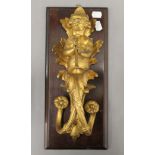 A 19th century ormolu wall mount formed as a cherub playing a trumpet, mounted on a wooden backing.