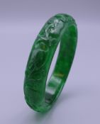 A Chinese carved apple green jade bangle. 7 cm diameter.