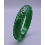 A Chinese carved apple green jade bangle. 7 cm diameter.