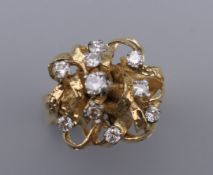 A diamond dress ring of abstract design with scattered brilliant cut diamond cluster to openwork