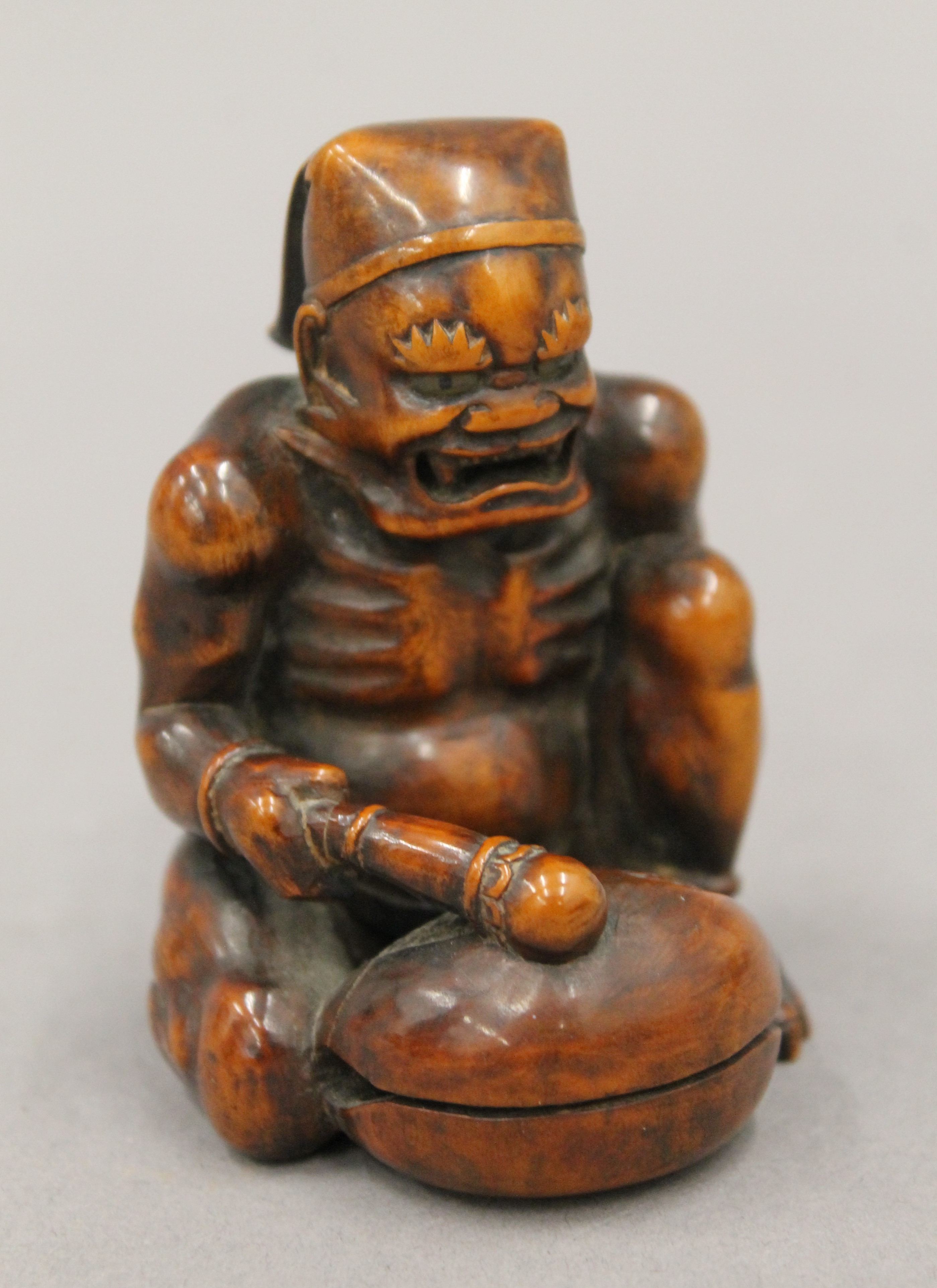 A boxwood okimono formed as a figure banging a drum. 7.5 cm high.