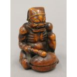 A boxwood okimono formed as a figure banging a drum. 7.5 cm high.