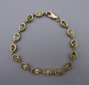 A 9 ct gold and peridot tennis bracelet. 18 cm long.