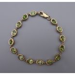 A 9 ct gold and peridot tennis bracelet. 18 cm long.