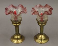 A pair of brass and cranberry tinged glass candlesticks. Each 24.5 cm high.