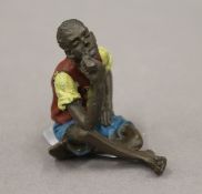 A painted bronze model of a boy smoking. 5.5 cm high.