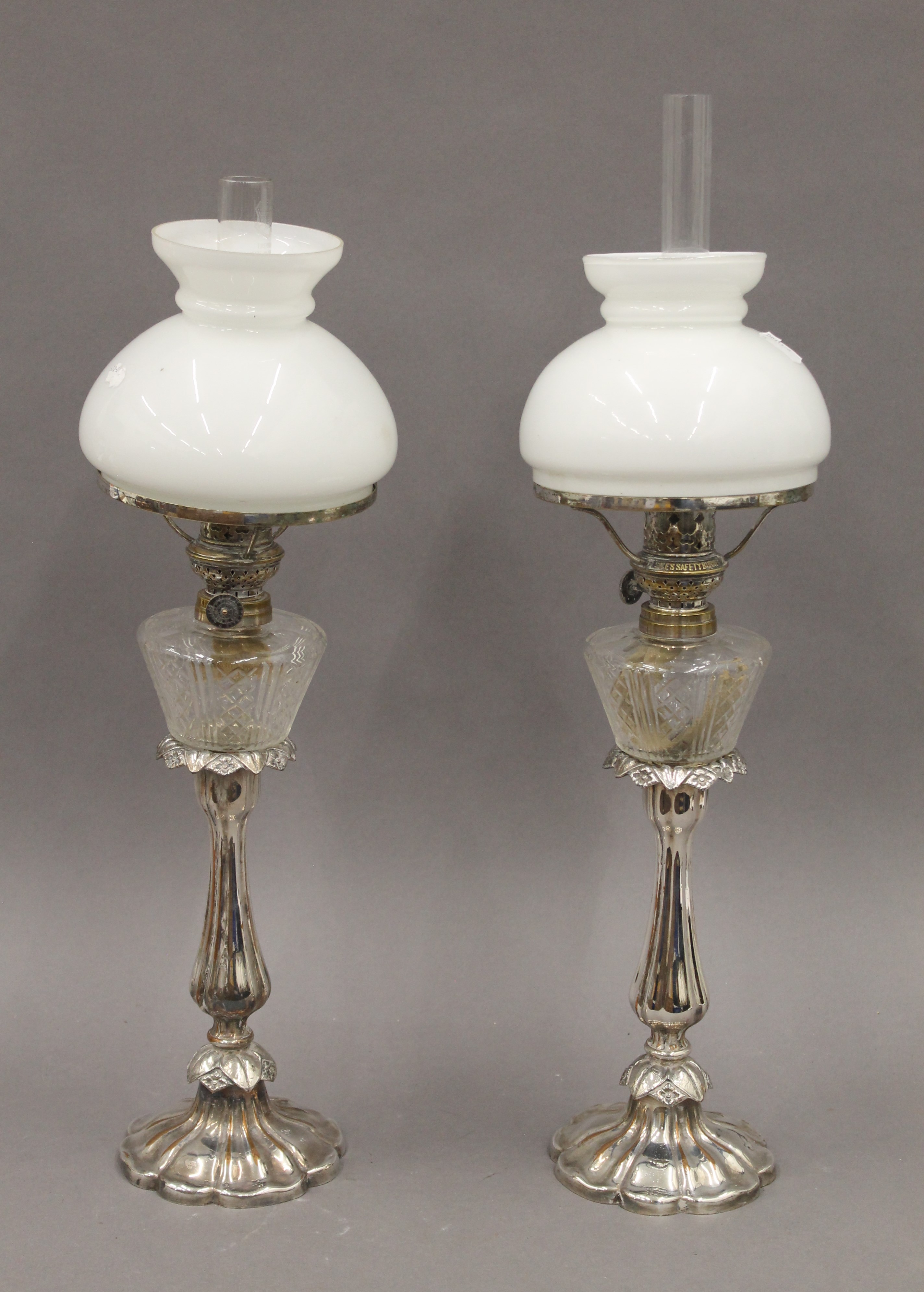 A pair of Victorian silver plated oil lamps, with cut glass reservoirs and opaline shades.