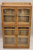 A Liberty style leaded glazed four door bookcase. 107 cm wide, 30.5 cm deep, 178 cm high.