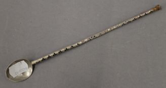 An enamelled decorated unmarked white metal cocktail spoon. 21.5 cm high.