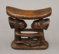 A tribal carved wooden headrest formed as two figures. 19 cm high.