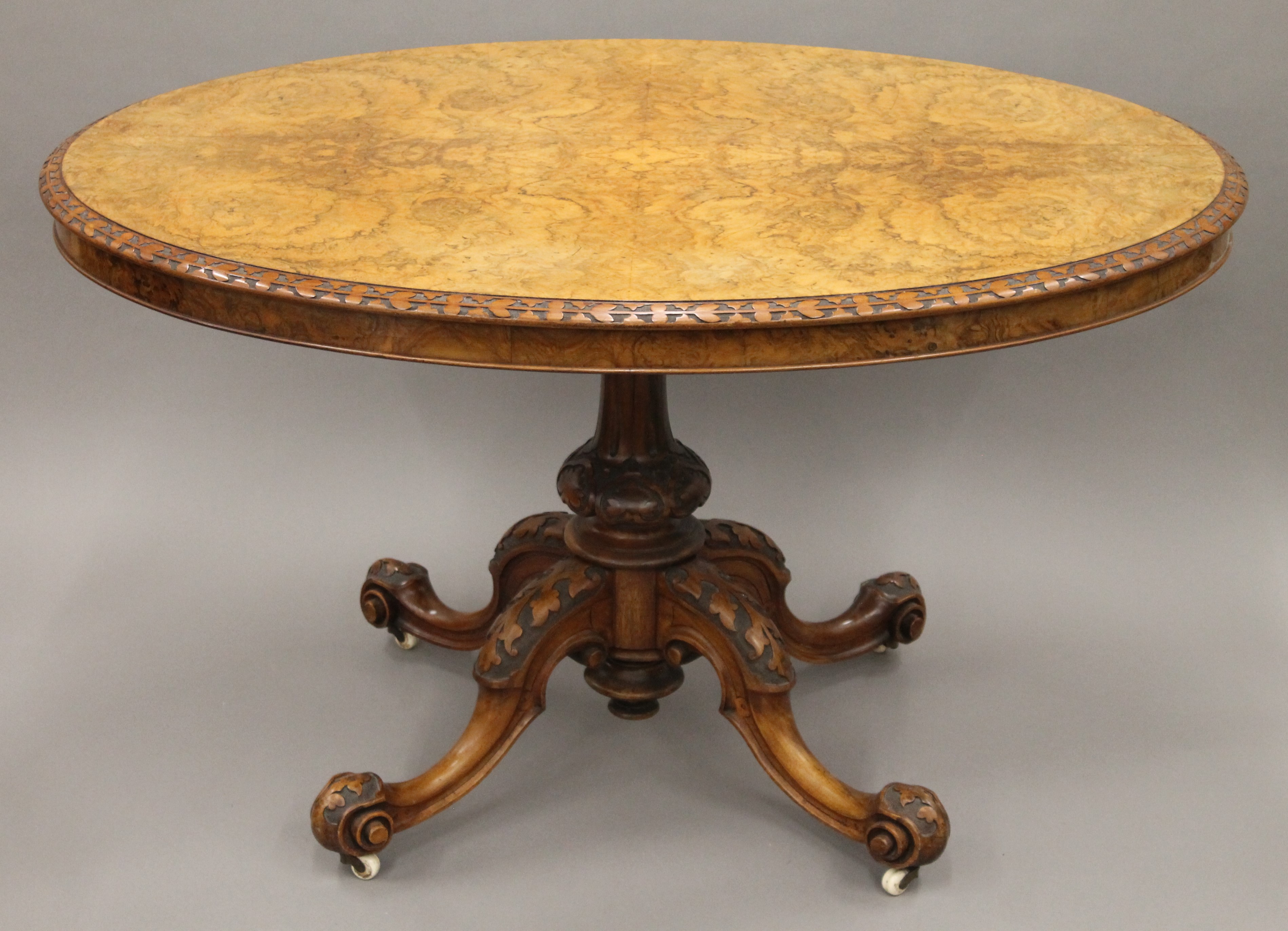 A burr walnut loo table with floral carved border. 122 cm long.