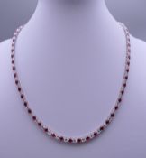 A 925 silver and rhodium plated synthetic ruby and diamond necklace. Approximately 40 cm long.