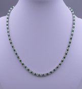 A 925 silver and rhodium plated synthetic emerald and diamond necklace. 40.5 cm long.