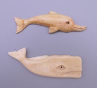 A carved bone model of a whale and a carved bone model of a dolphin. The largest 8 cm long.