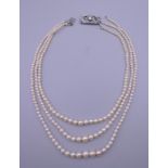A platinum and diamond clasp three strand pearl necklace.