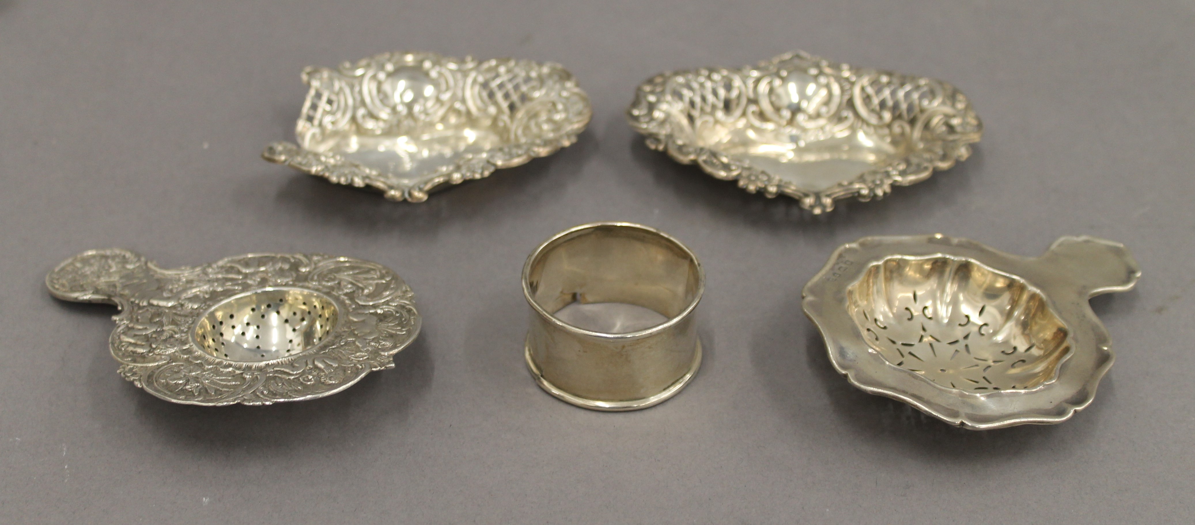 A pair of silver pierced dishes, a napkin ring and two strainers. The former 10 cm wide. 3.