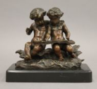 A marble based bronze model of two children writing. 13.5 cm wide.