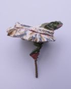 A cold painted model of a frog and a bottle top. 4 cm wide.