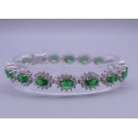 A 925 silver and rhodium plated synthetic emerald and diamond bracelet. 18 cm long.