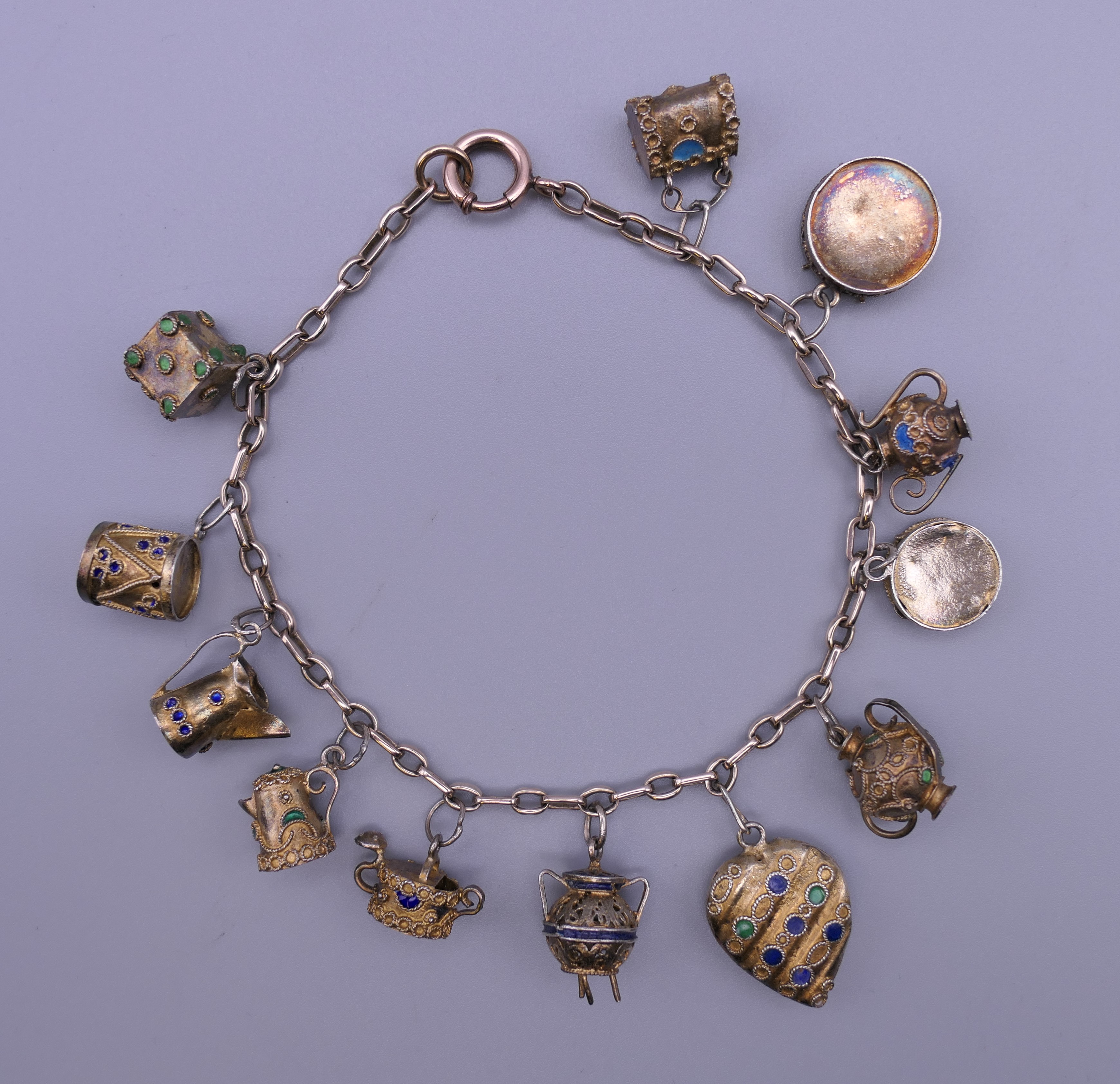 A unmarked gold bracelet with twelve silver gilt and enamelled charms. Approximately 18 cm long.