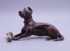 A cold painted bronze model of a dog and bone. 7 cm long.