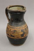 A brown and black glazed pottery jug. 26 cm high.