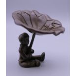 A Japanese bronze model of a boy holding a lily pad. 6.5 cm high.