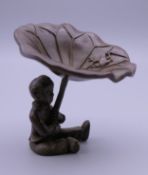 A Japanese bronze model of a boy holding a lily pad. 6.5 cm high.