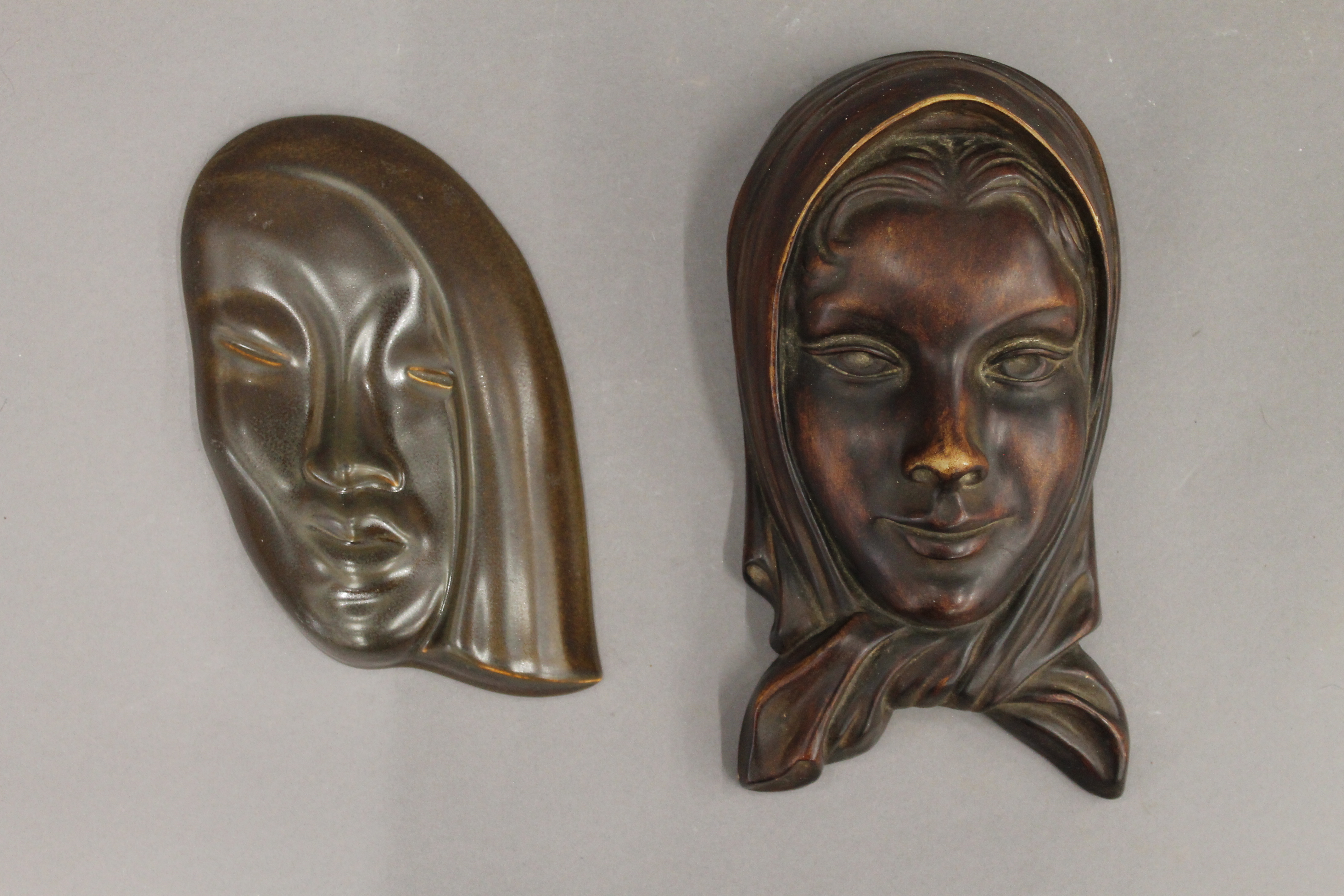 An Art Deco porcelain wall mask and another. The former 23 cm high.