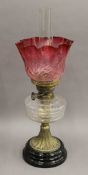 A Victorian oil lamp with cranberry glass shade. 56 cm high overall.