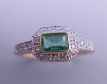 An Art Deco style 9 ct gold emerald and diamond ring with engraved shoulders. Ring size O.