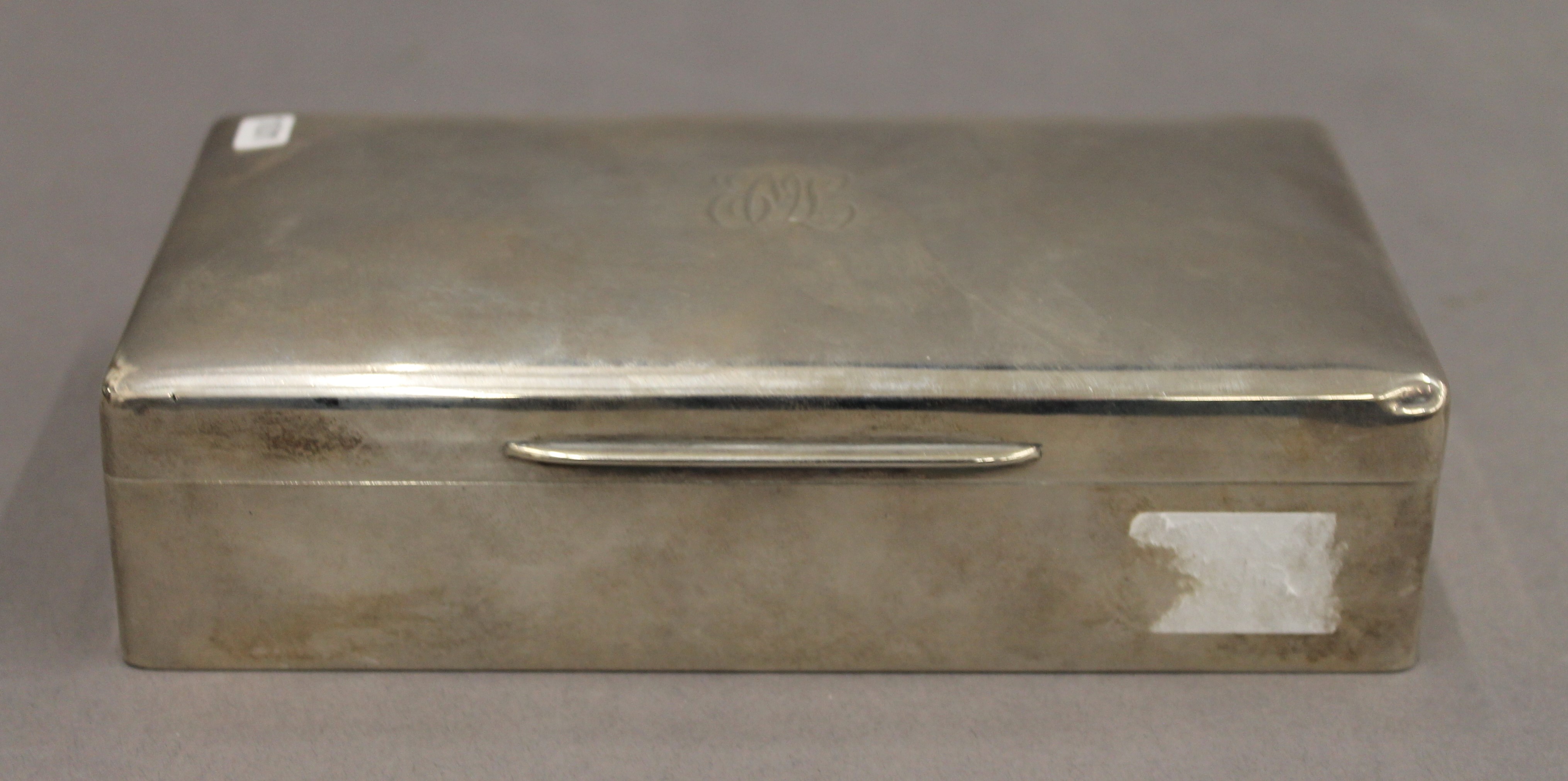 A silver cigarette box. 18 cm wide. 12.2 troy ounces total weight.