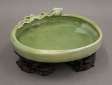 A 19th century Chinese celadon shallow dish on a carved wooden stand. 22 cm wide.