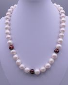 An 18ct gold enamel and diamond set pearl necklace. Approximately 44 cm long.