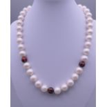 An 18ct gold enamel and diamond set pearl necklace. Approximately 44 cm long.