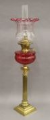 An oil lamp with cranberry glass reservoir. 80.5 cm high overall.