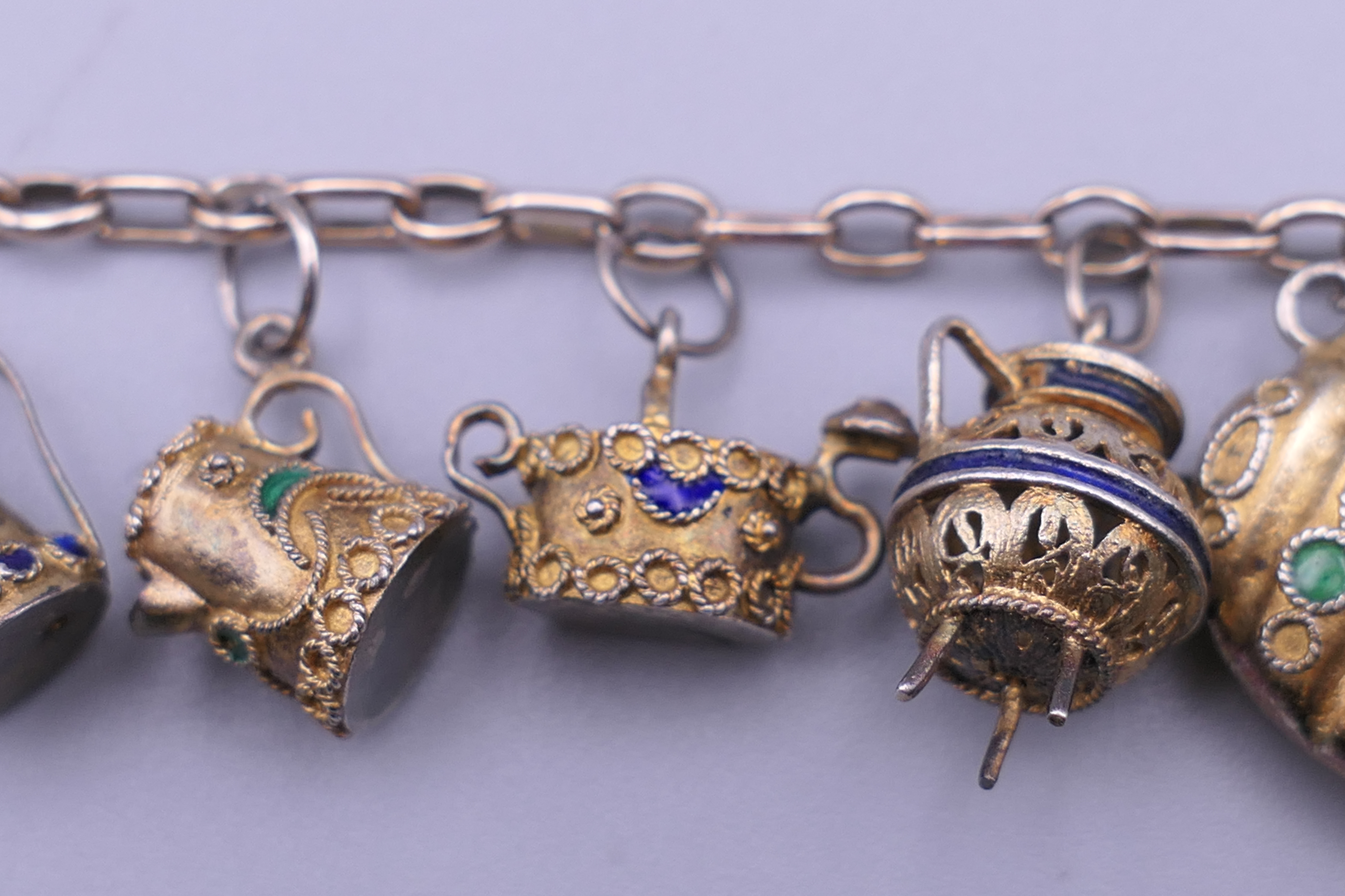 A unmarked gold bracelet with twelve silver gilt and enamelled charms. Approximately 18 cm long. - Image 3 of 6