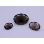 Three smokey quartz cut gemstones. The largest 3.5 x 2.5 cm.