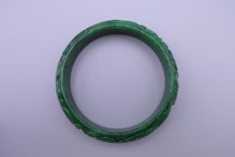 A carved apple green jade bangle. 7.5 cm diameter.