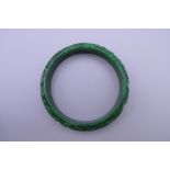 A carved apple green jade bangle. 7.5 cm diameter.