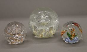 Three decorative glass paperweights. The largest 10 cm wide.