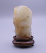 A Chinese carved jade model of a fisherman on a wooden stand. 6 cm high overall.