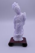 A lavender jade carving of Guanyin on a wooden stand. 11 cm high overall.