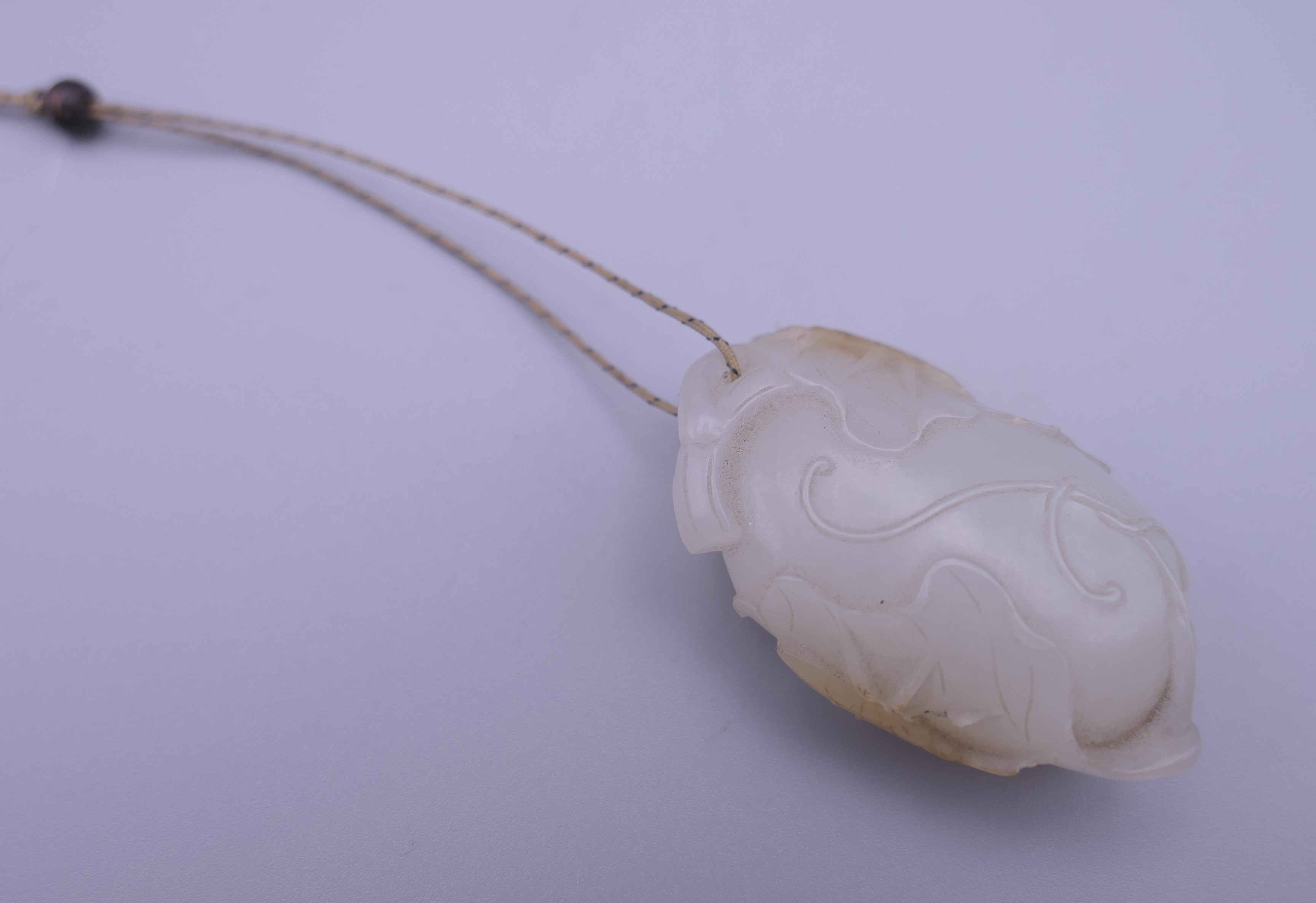 A Chinese mutton fat carved jade pendant, formed as insects on a flowering fruit. 4.5 cm high.