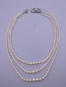 A platinum and diamond clasp three strand pearl necklace.
