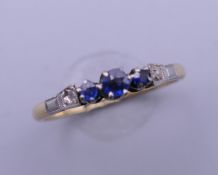 An 18 ct gold three stone sapphire ring. Ring size M. 2.2 grammes total weight.
