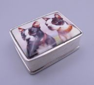 A silver pill box depicting two dogs. 3 cm wide.