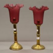 Two brass candlesticks with cranberry shades. The largest 39 cm high.