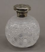 A silver topped cut glass perfume bottle. 11 cm high.